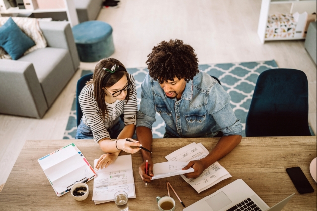 Couple study paperwork at a wooden table