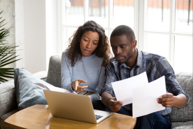 couple sitting on the sofa looking at a laptop together