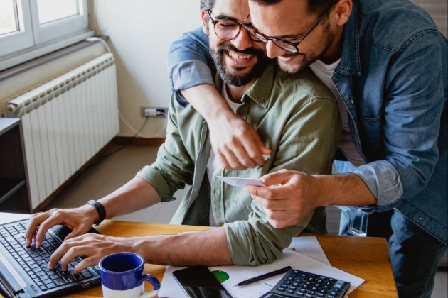 Couple sitting at a desk arm in arm looking at a computer