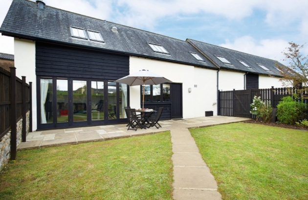 White house with black details, bifold doors and a garden area