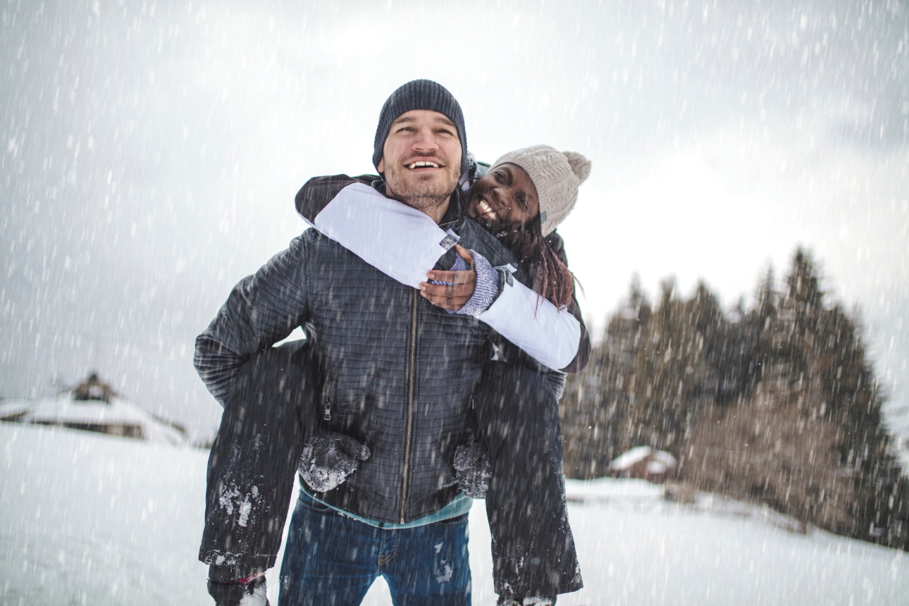 man giving woman a piggyback in the snow 