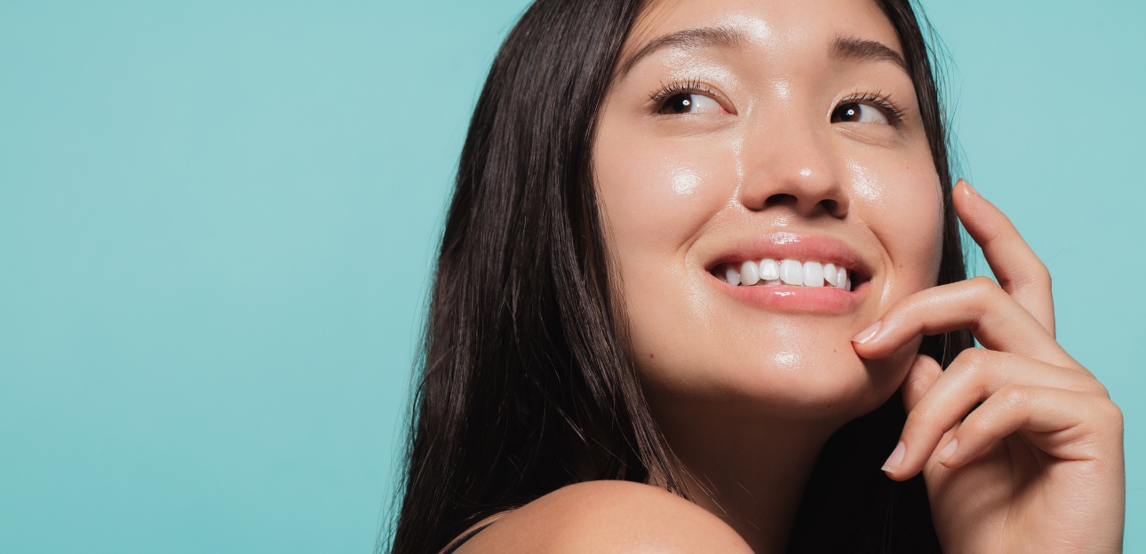 Young woman with glowing skin against a blue background