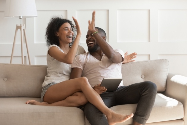 couple on sofa with ipad high-fiving 