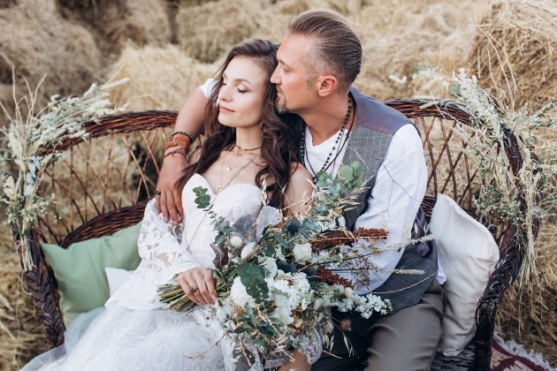 couple in relaxed wedding attire sitting on chair in front of haybales