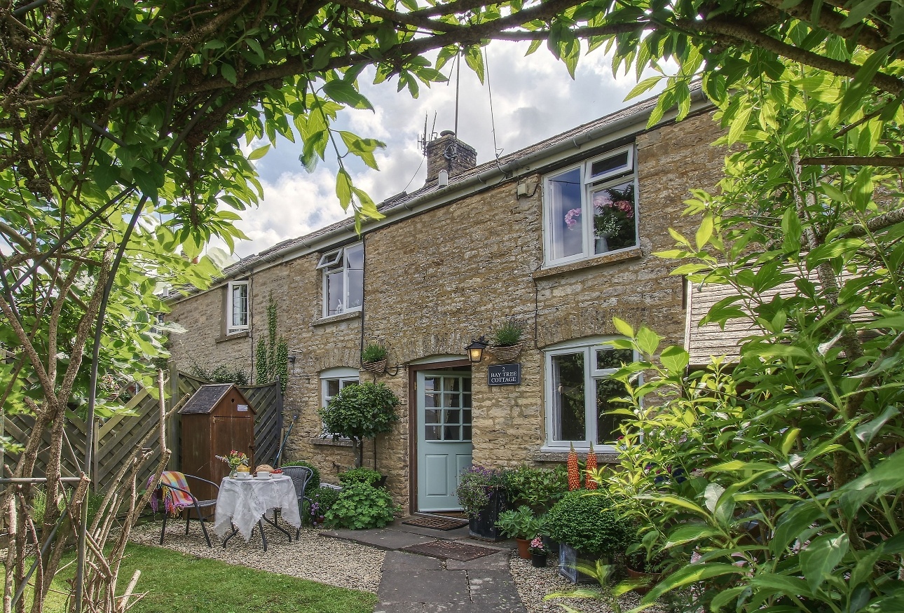 stone cottage with table and chairs in closed off garden