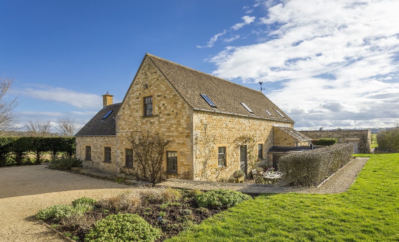 yellow stone cottage, manicured garden fields around sunny day 