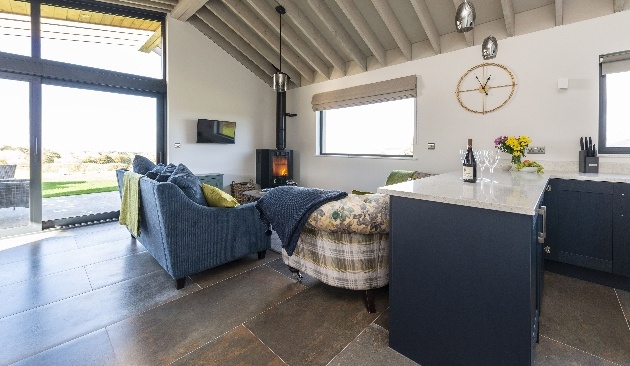 open plan living room blue sofa and log burner large windows with views