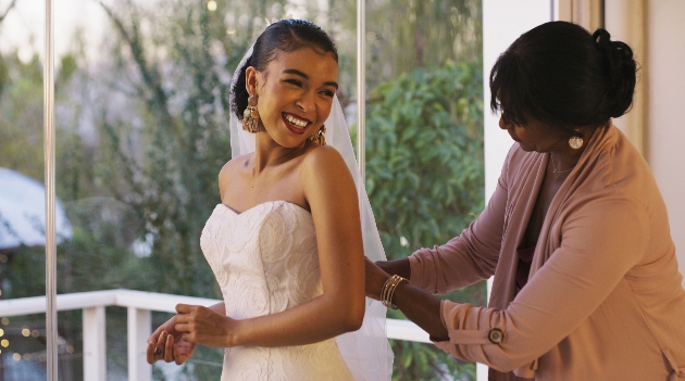 bride with mum helping her get dresses in wedding gown