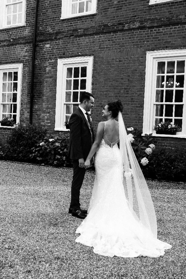 black and white photo of wedding couple standing in front of house