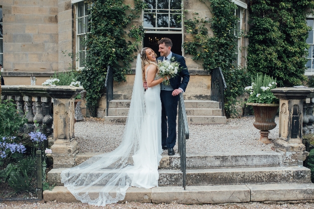 couple in their wedding attire standing on steps outside of their wedding venue