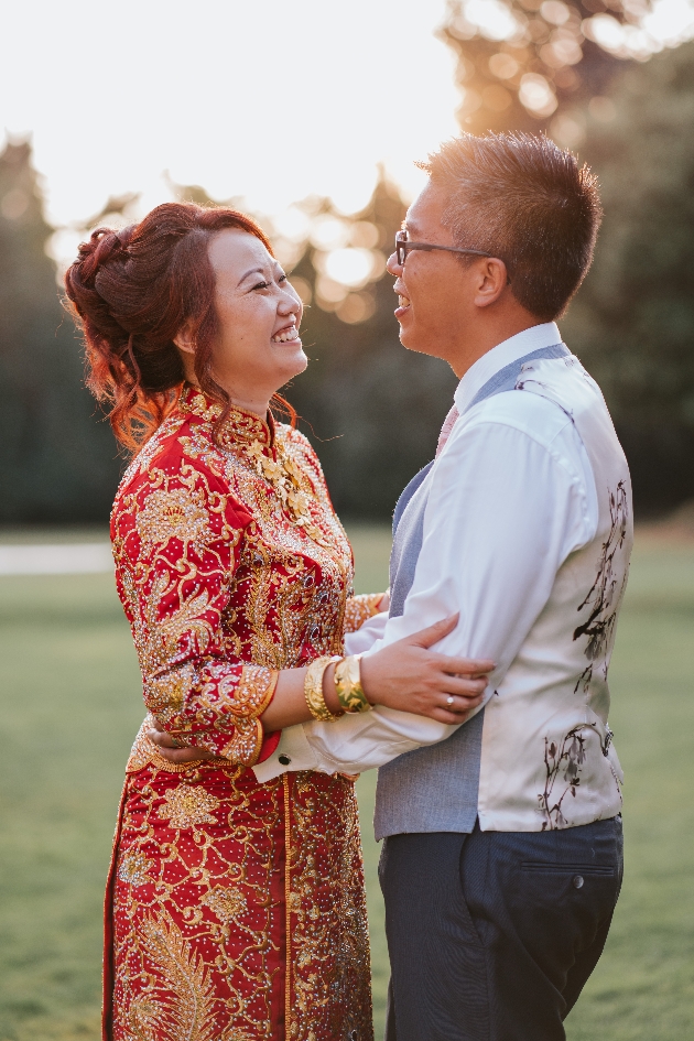 bride and groom in traditional Chinese wedding outfits hugging outside at sunset