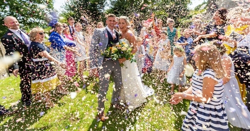 bride and groom in crowed of people having confetti thrown at them