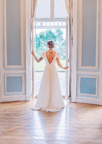 bride in lace gown looking out of the window of a historic house in blue and white room