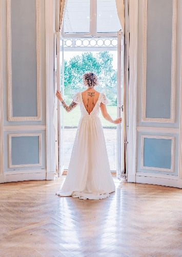 bride in lace gown looking out of the window of a historic house in blue and white room