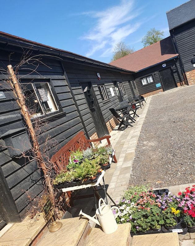 black wooden barn-style building with a gravel front garden