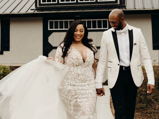 bride and groom walking along groom in black and white tux and bride in a curvy gown of lace