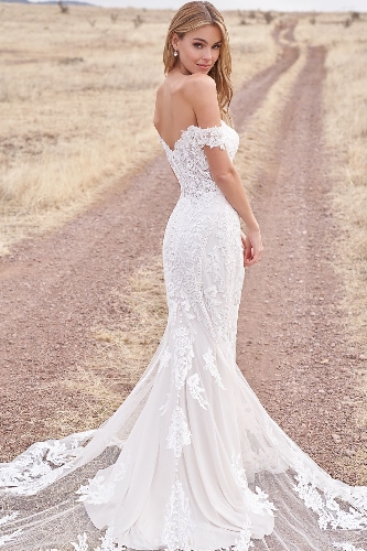 model in a lace fishtail gown standing in a field