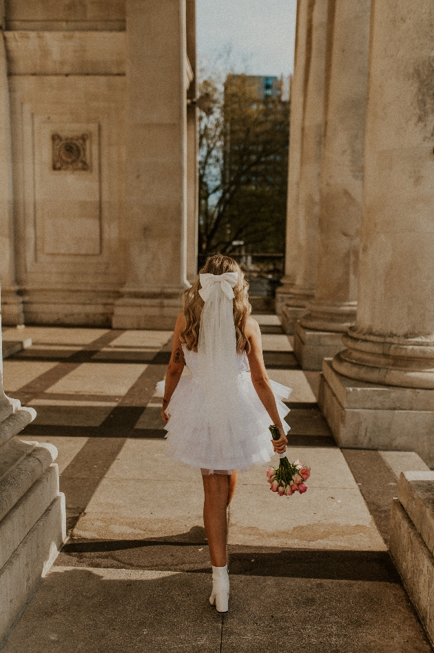 bride in mini dress in white with veil and bouquet