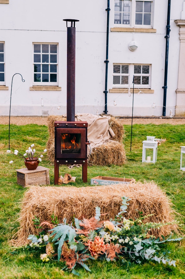 wood burner stove outside surrounded by hay bales and flowers