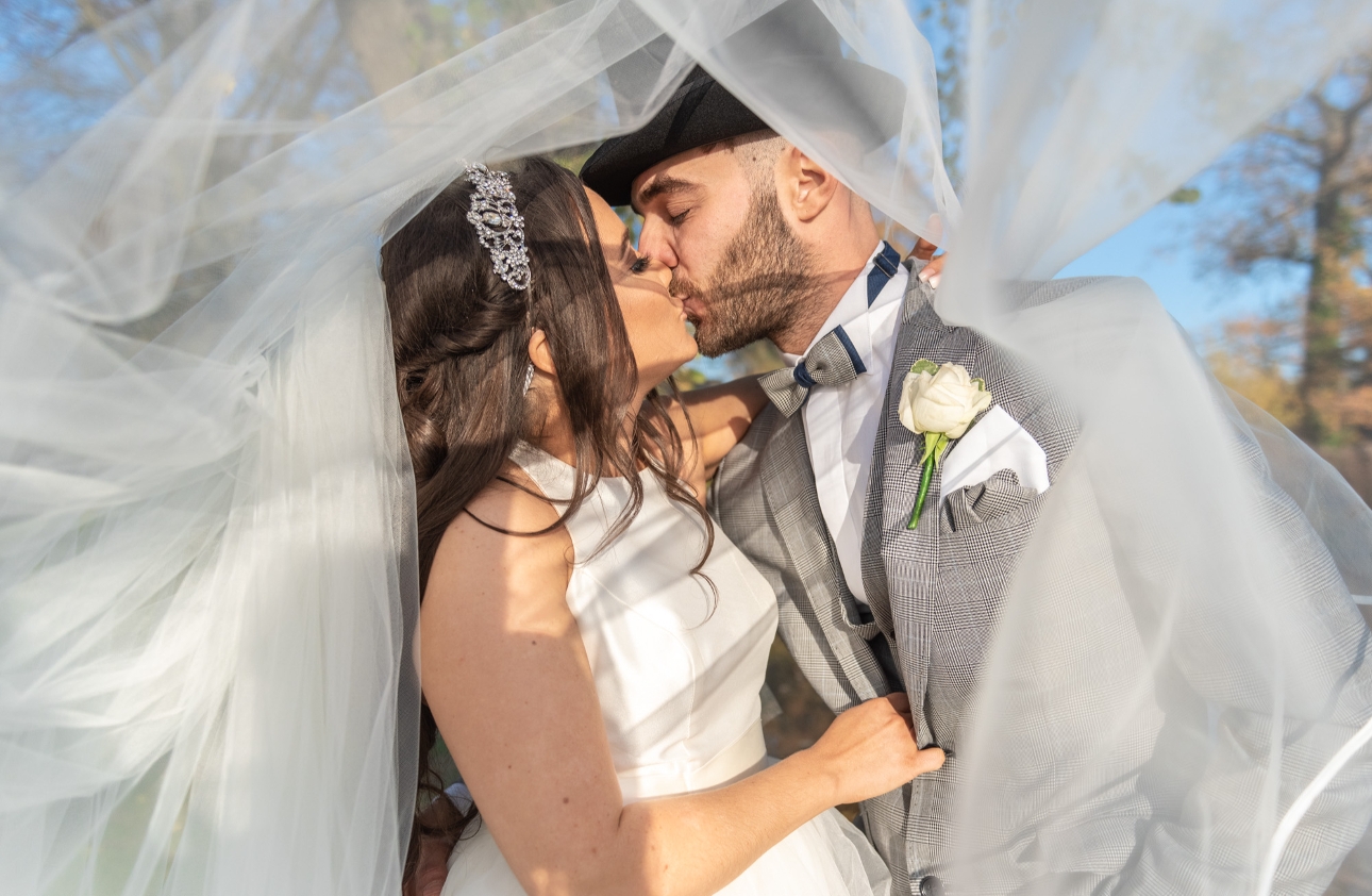 bride and groom kissing under a veil