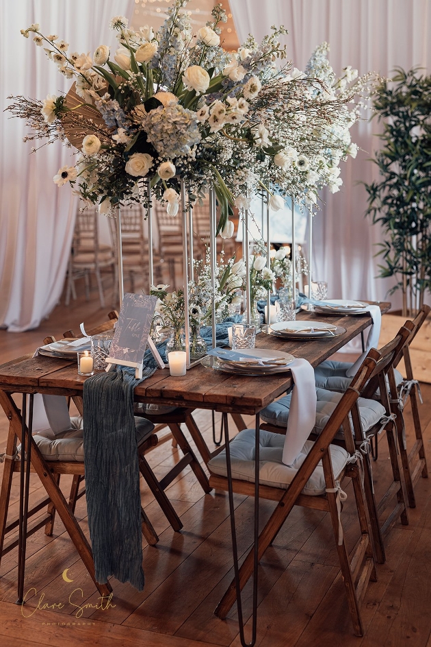 wooden trestle table set up with flowers, plates and candles etc