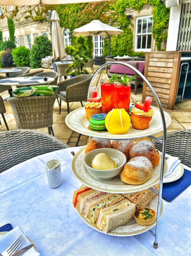 tennis themed afternoon tea on table outside with luxury hotel in the bakground