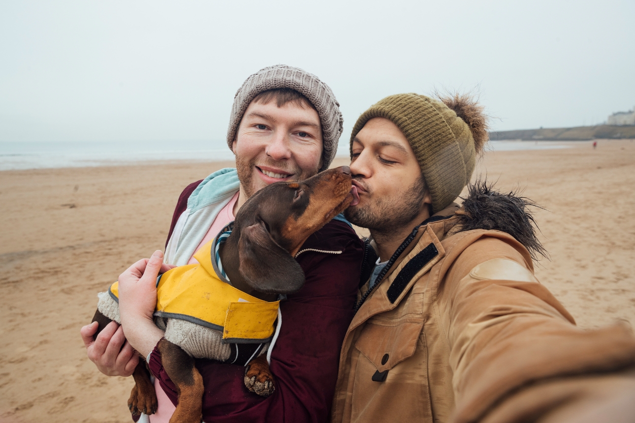 two men on beach with their dog 