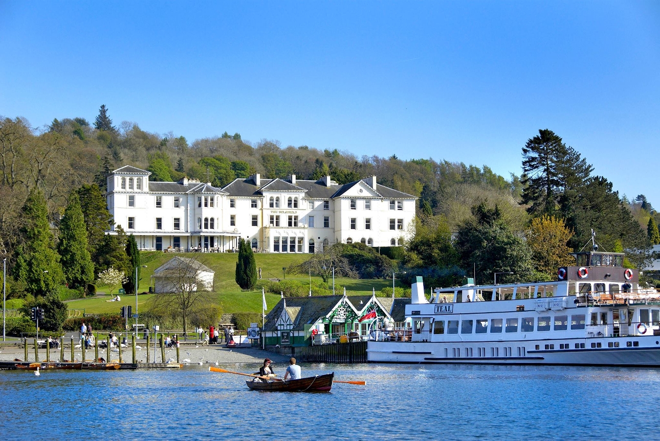 hotel on banks of river atop a small hill lake in view on sunny day