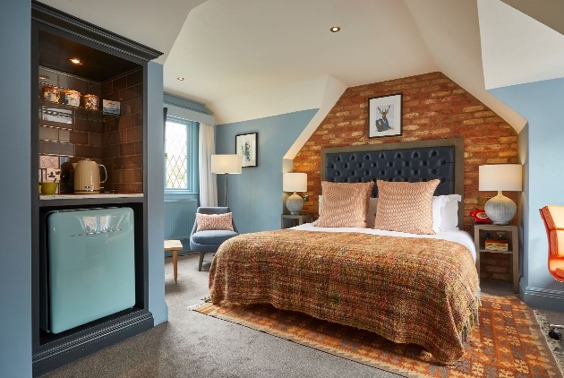 bedroom, light blue walls, brick bed head, large bed, blue fridge