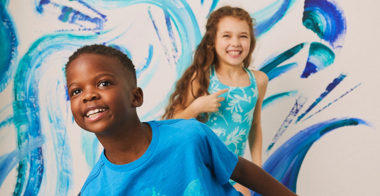 Boy in blue t-shirt in front of girl in blue swimming costume