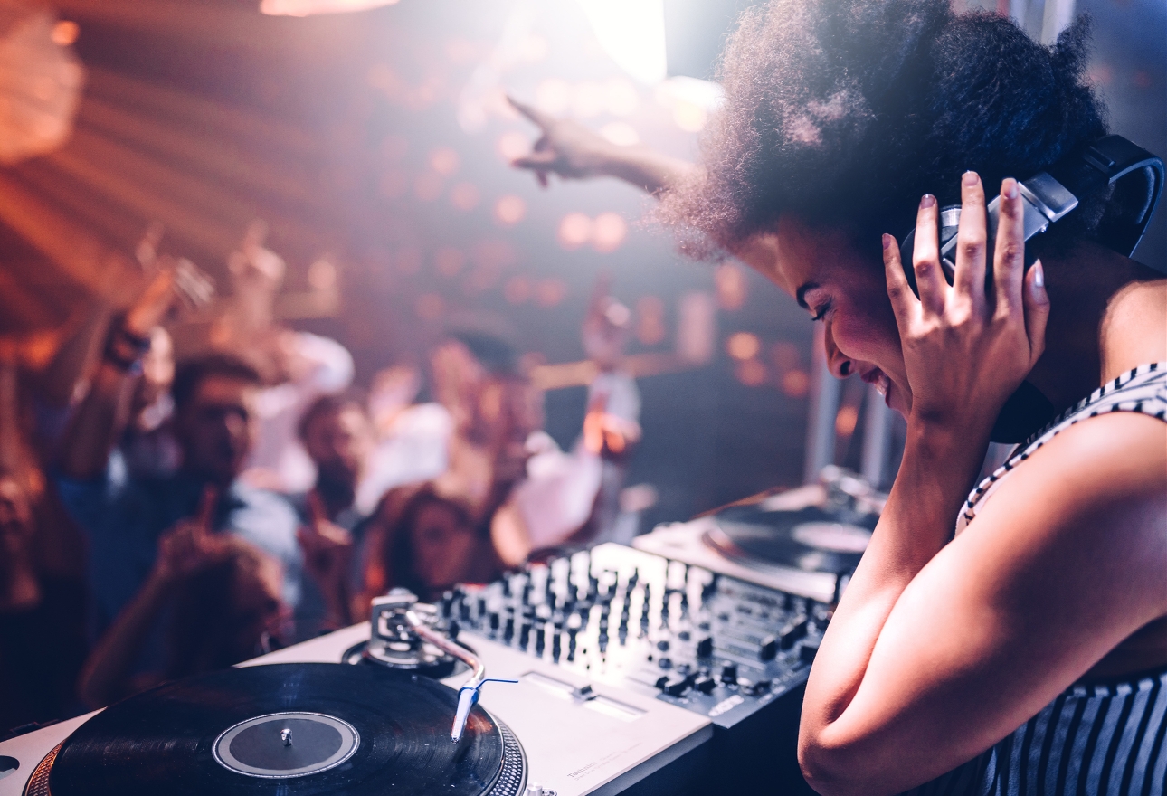 DJ at decks pointing to cheering crowd