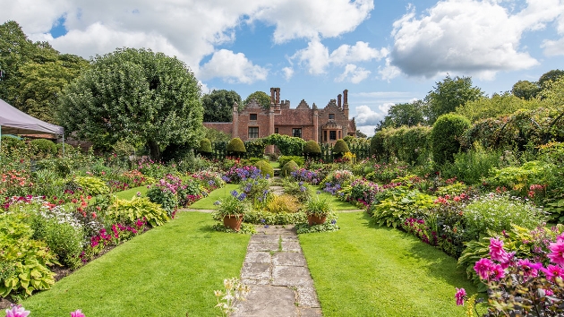 county house in red brick set in middle of manicured gardens