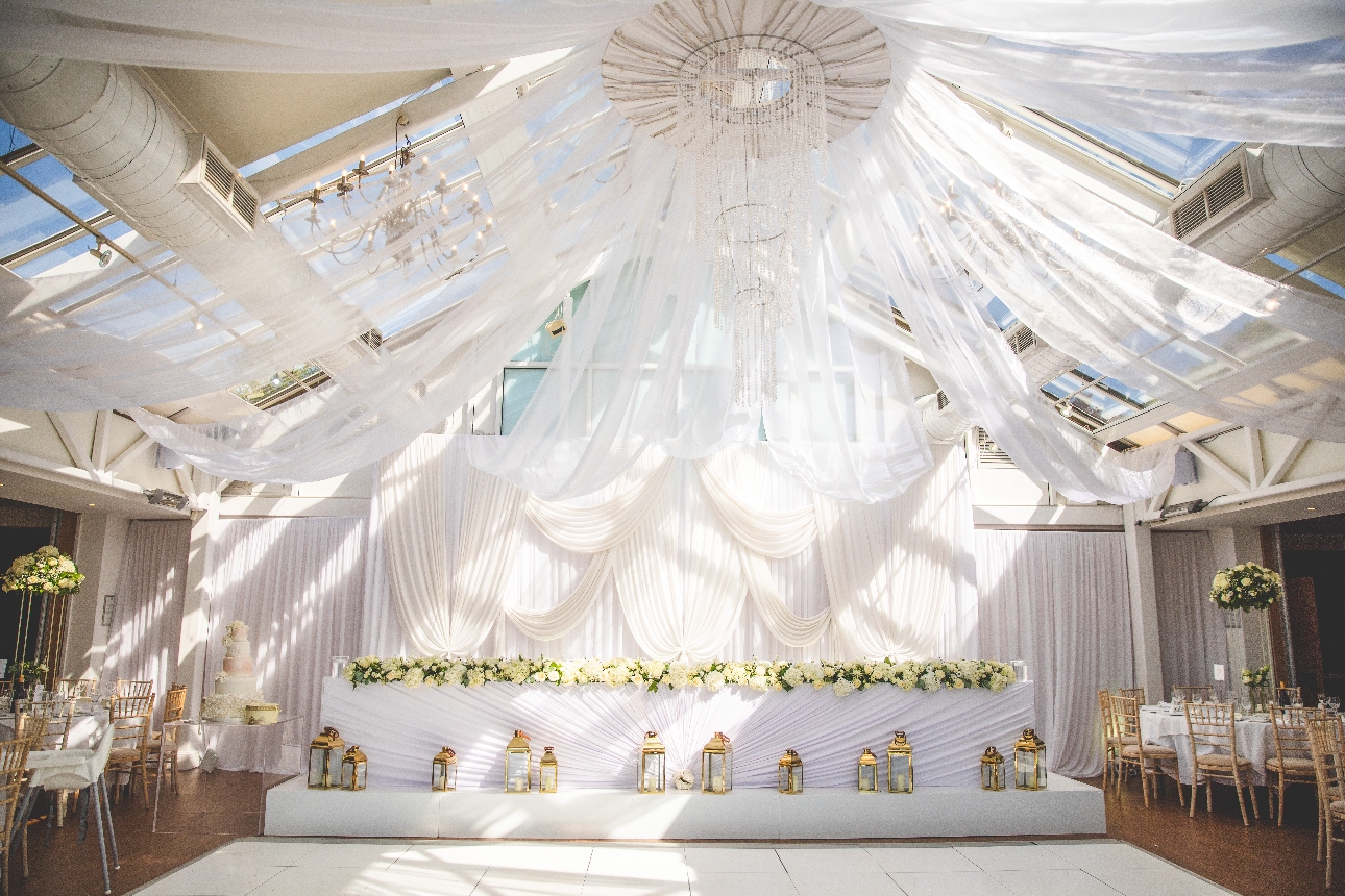 large glass conservatory with crystal chandelier with white draping