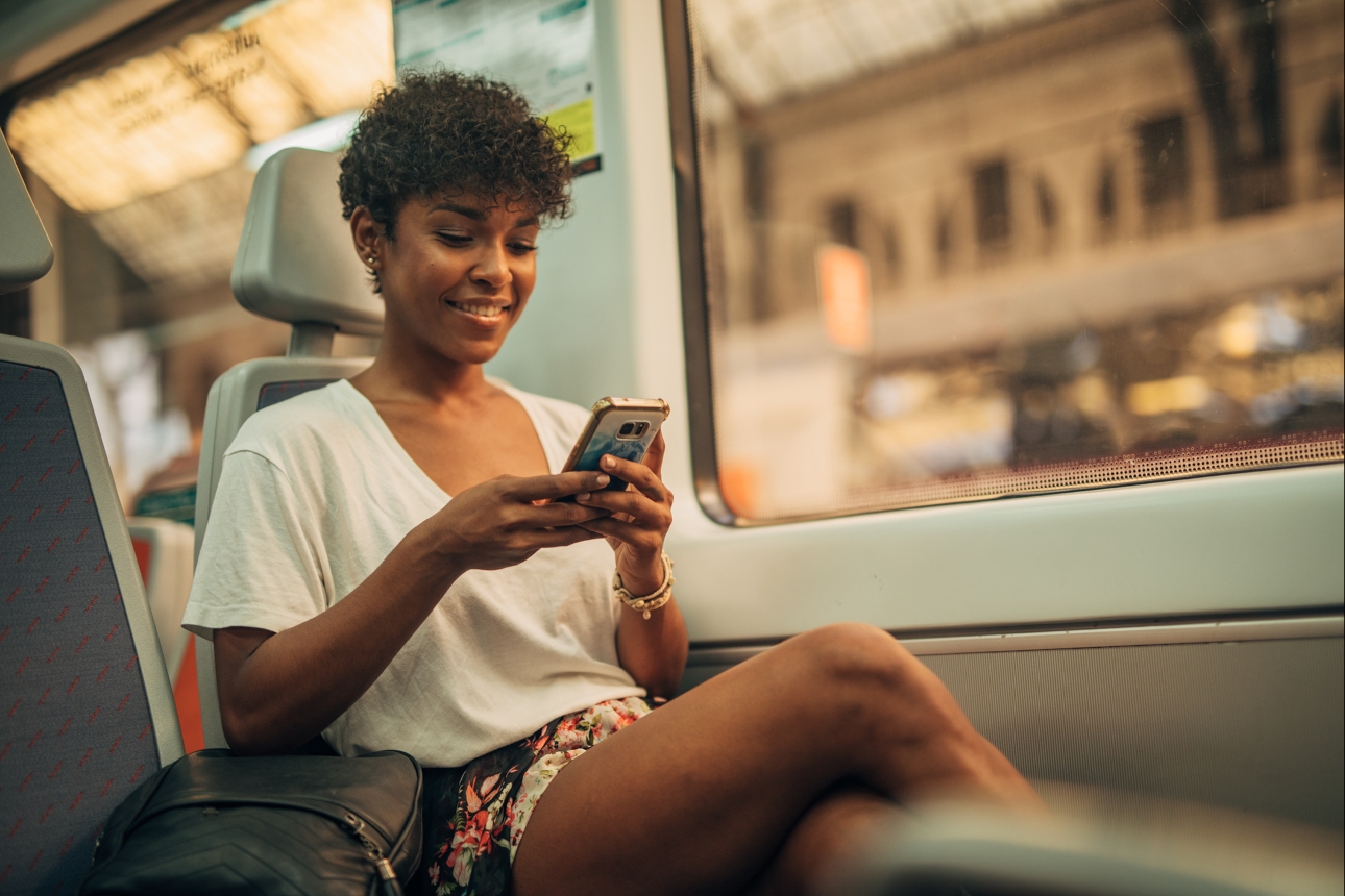 woman sat on train looking at her phone