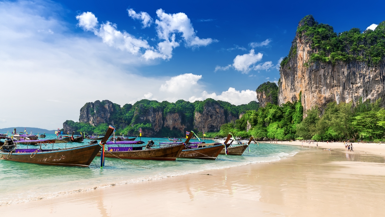 beach with ocean and fishing boats and cliffs in view on a sunny day