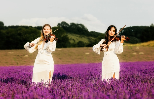 two violinists in field in white dresses