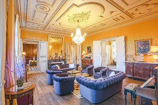 Sofas and chairs surrounded by luxurious furniture and a decorated ceiling