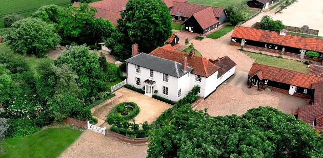 white country house with farm out buildings around in and trees