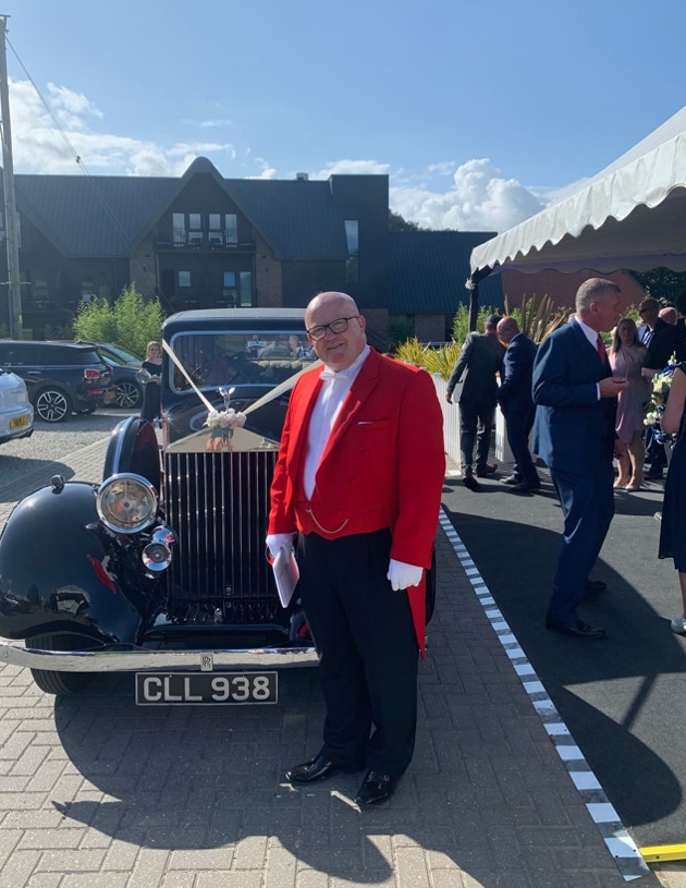 Toastmaster John in uniform by wedding car