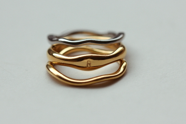three ring in a pile one with an initial on it