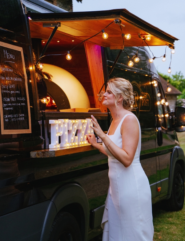 bride ordering a slice of pizza from a pizza van