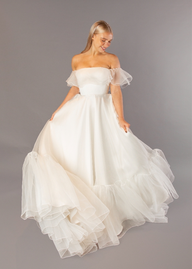 model in strapless dress with waterfall ruffle skirt just at bottom hem and around shoulders