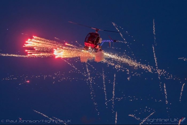 helicopter in sky at night with fireworks coming out of the bottom