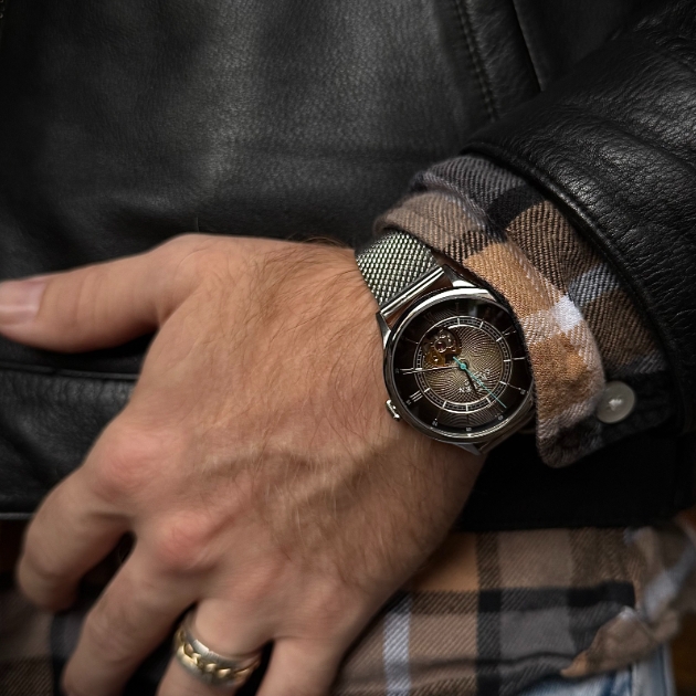 man styling a silver mesh watch