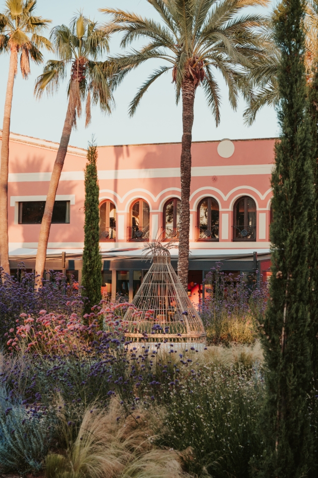 outdoor of hotel, low rise, pink building, surround by foliage gardens