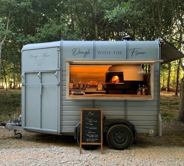 Wood-fired pizza oven in action at a Dough with the Flow wedding catering event