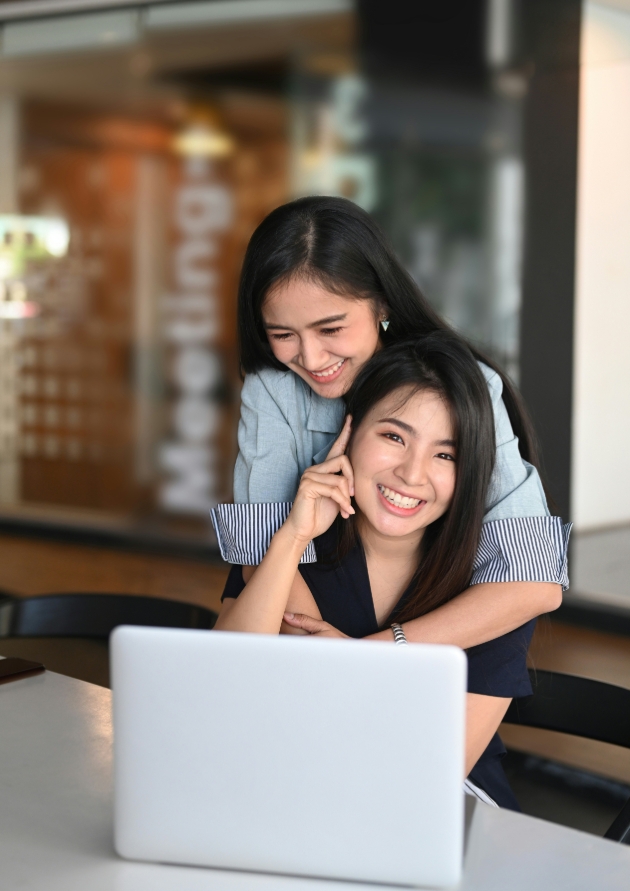 couple embracing with one sat at a computer