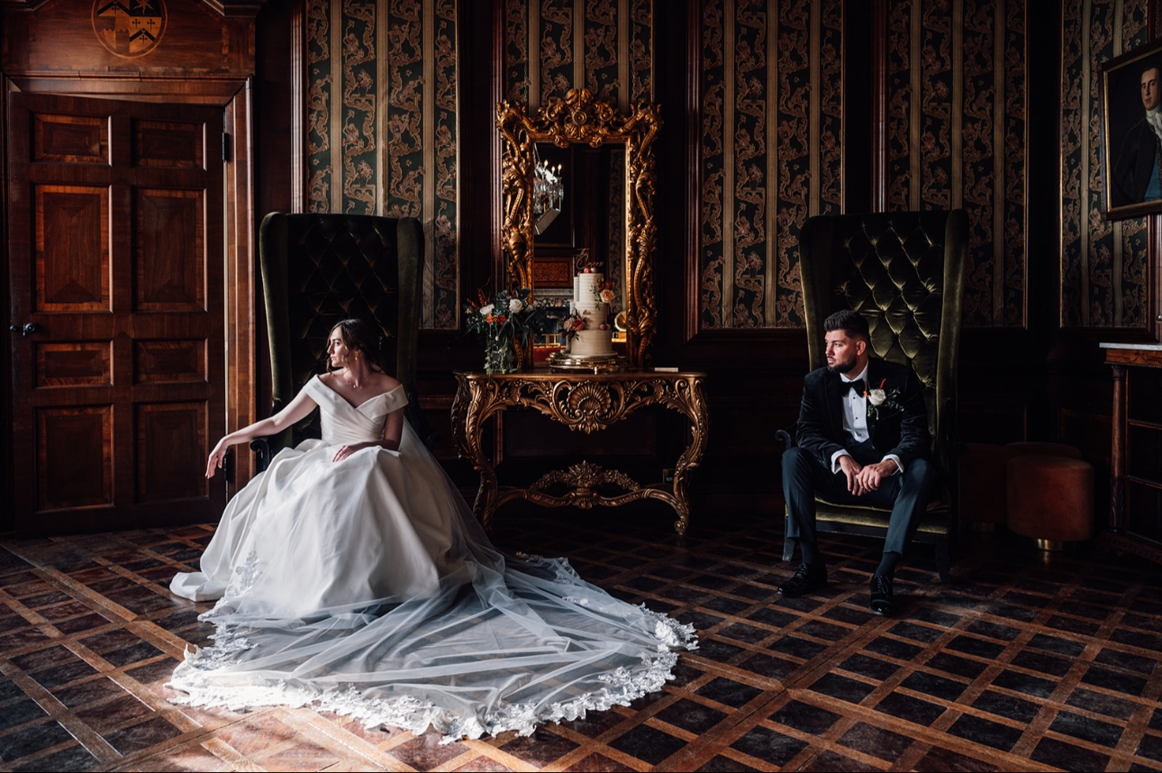 bride and groom sat in chairs in a manor house